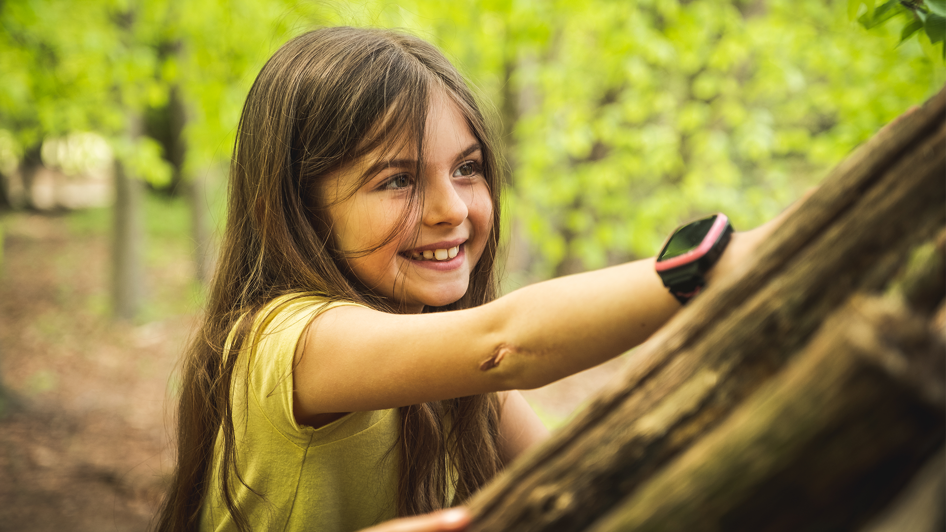 Flicka med Xplora X5-klocka leker i skogen.