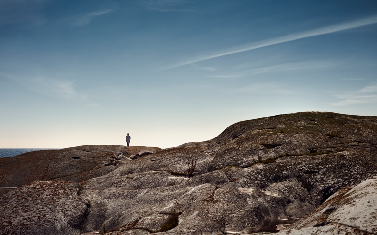 Landskapsbild med person som står på rund klipphäll.