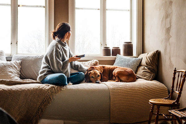 Kvinna med telefon och hund i soffa