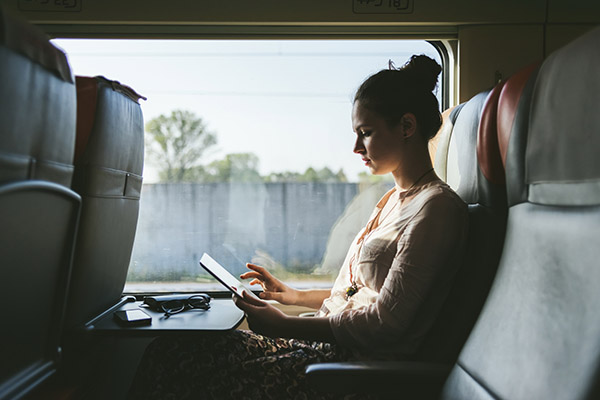 Ung kvinna med surfplatta på tåg