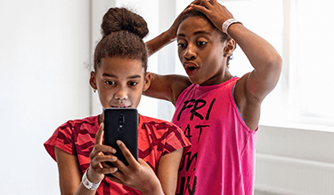 Två barn tittar på en mobiltelefon.
