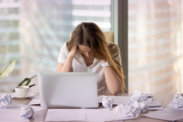 Kvinna förtvivlad på kontor framför dator