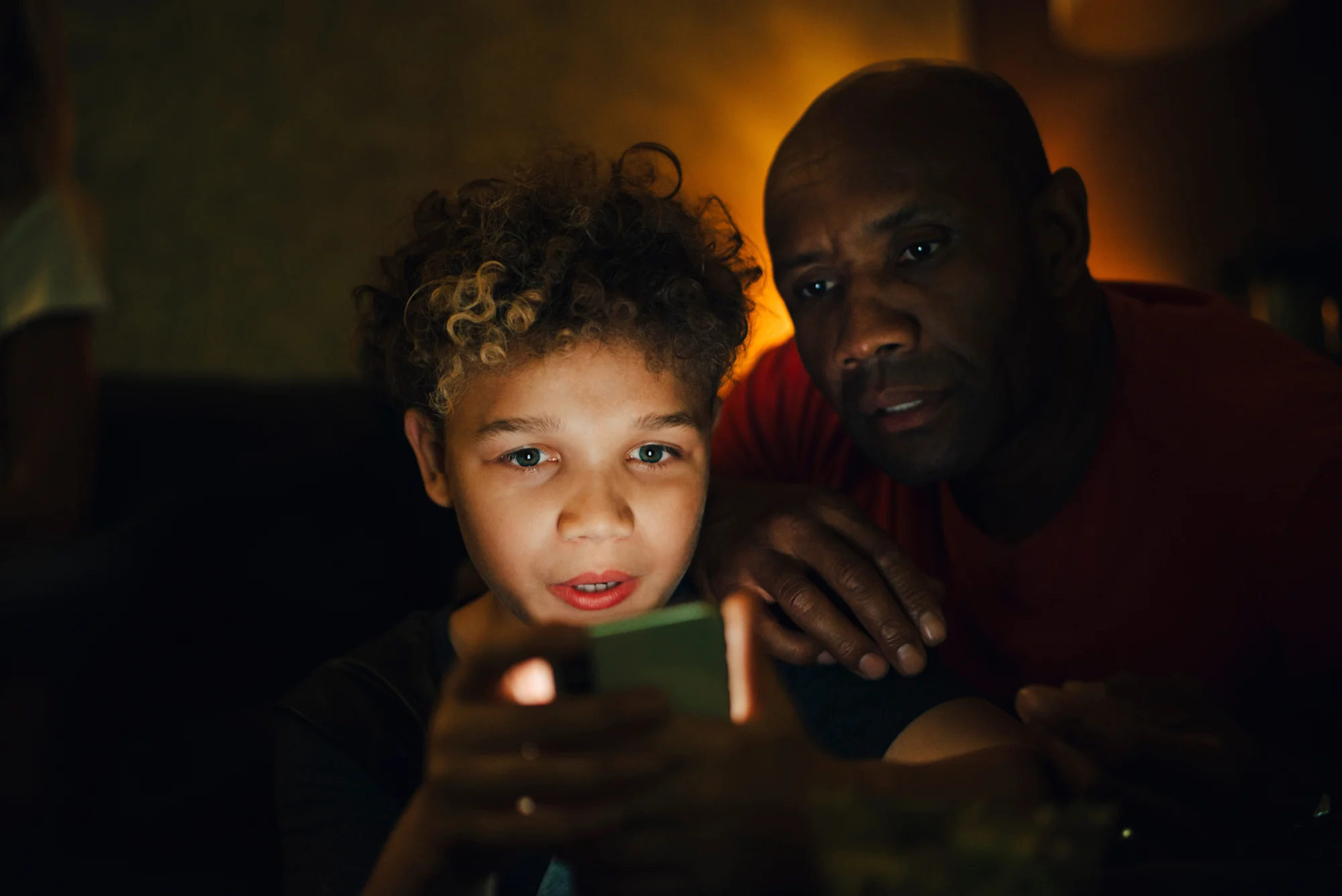 Pojke och man tittar på surfplatta mörkt rum