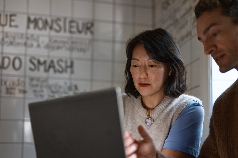 Man visar kvinna på laptop på café