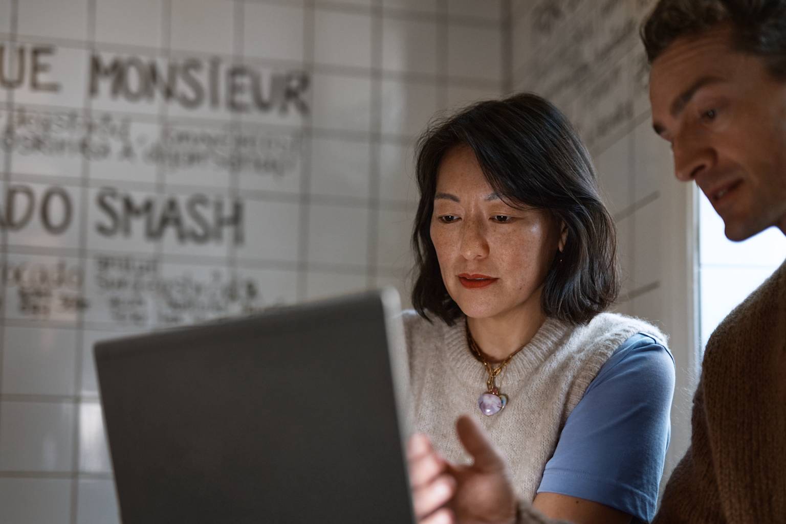 Man visar kvinna på laptop på café