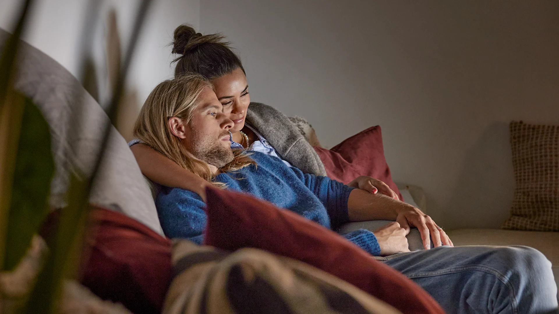 Ett yngre par sitter tillsammans i soffan och tittar på tv.