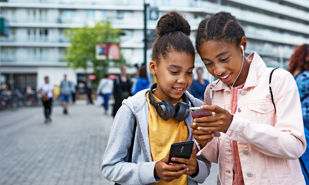 Två syskon tittar på en mobiltelefon.