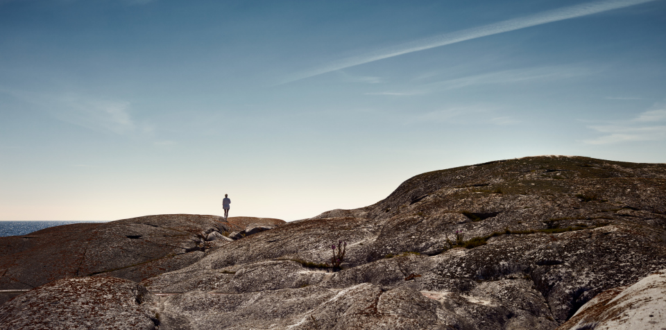 Landskapsbild med person som står på rund klipphäll.