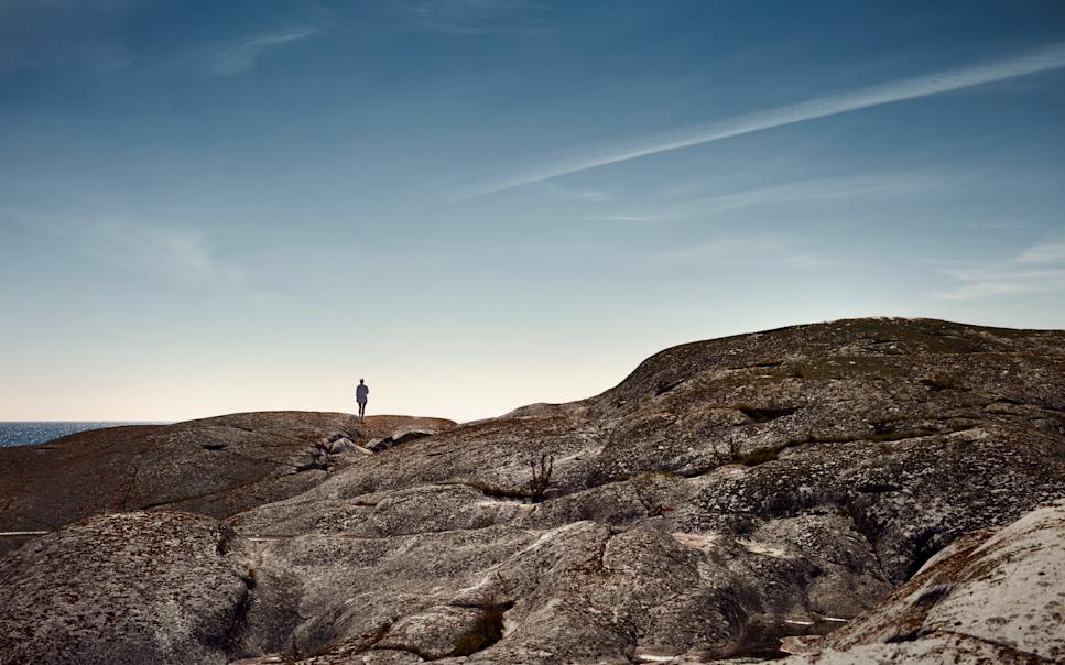 Landskapsbild med person som står på rund klipphäll.