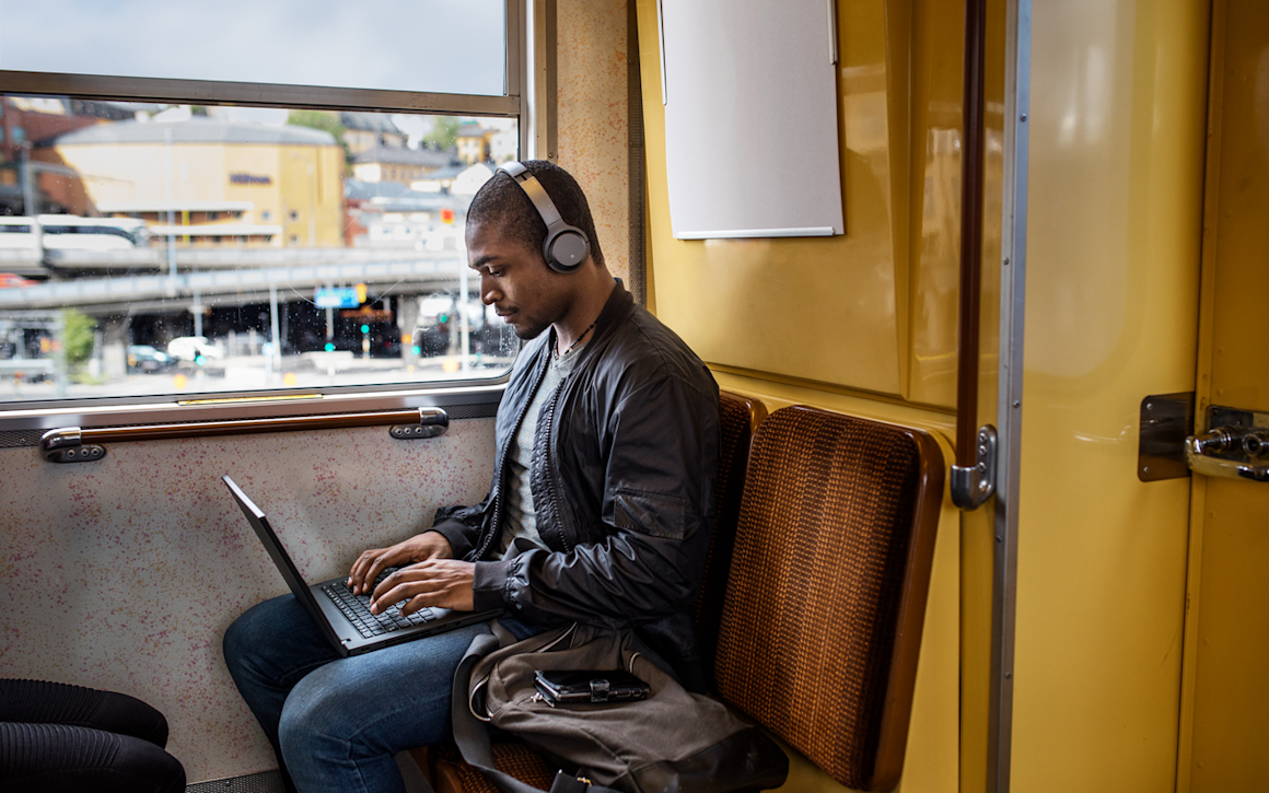 Kille på tunnelbanan med laptop och hörlurar
