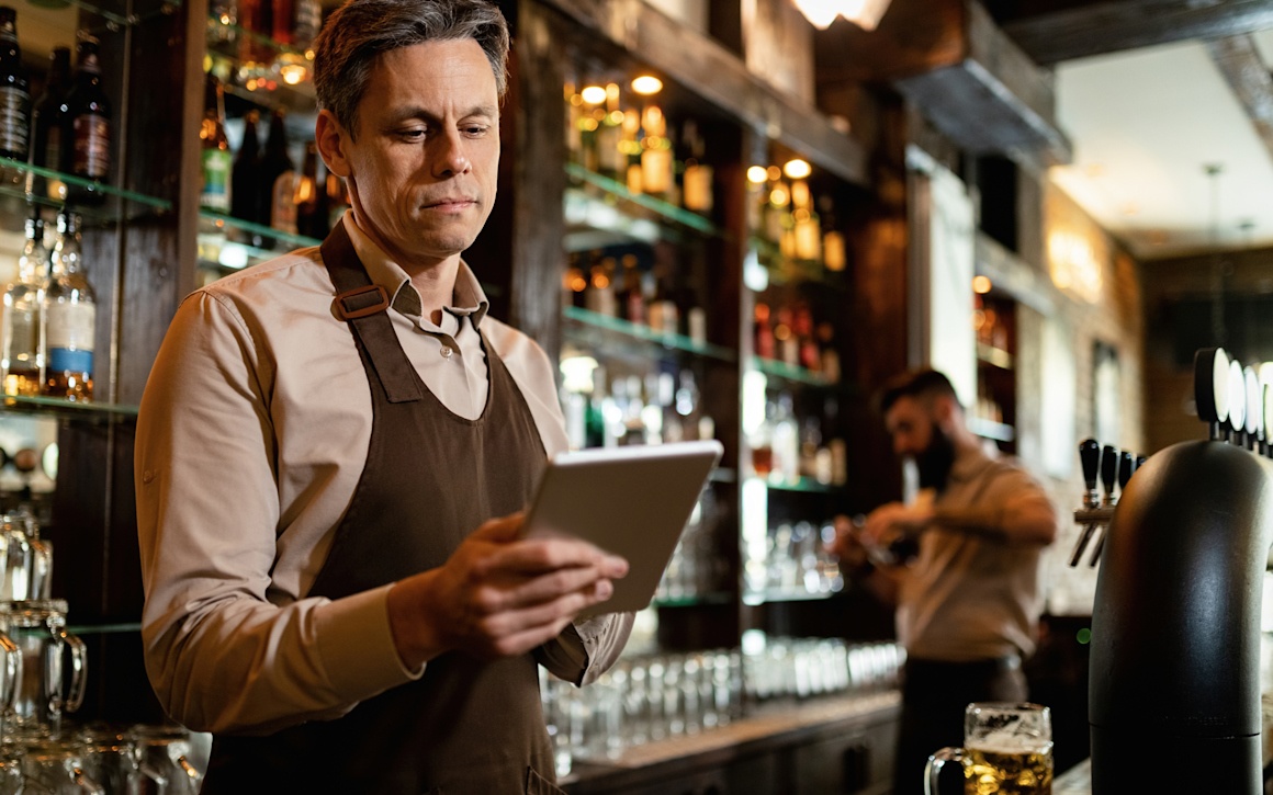 Man kollar kassan på surfplatta på restaurang.