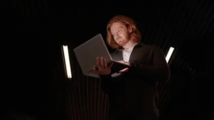 Man med rött hår och skägg som tittar på en dator