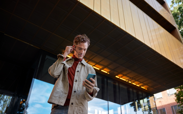 Manlig företagare pratar i mobil med hörlurar utomhus.