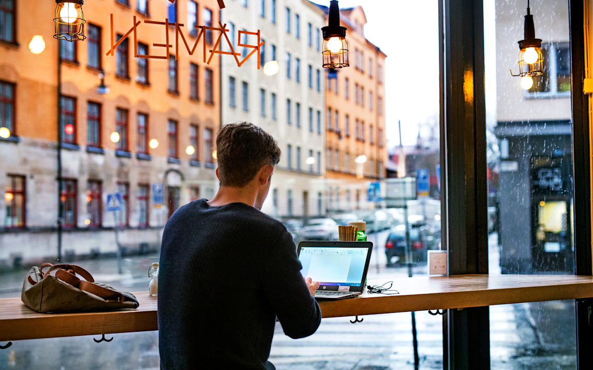Man arbetar på laptop på restaurang.