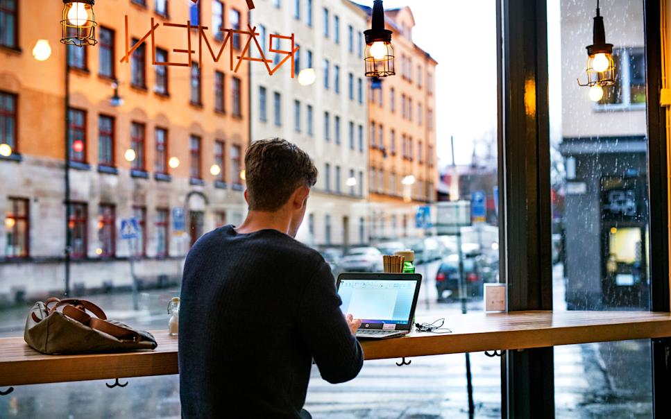 Man arbetar på laptop på restaurang.