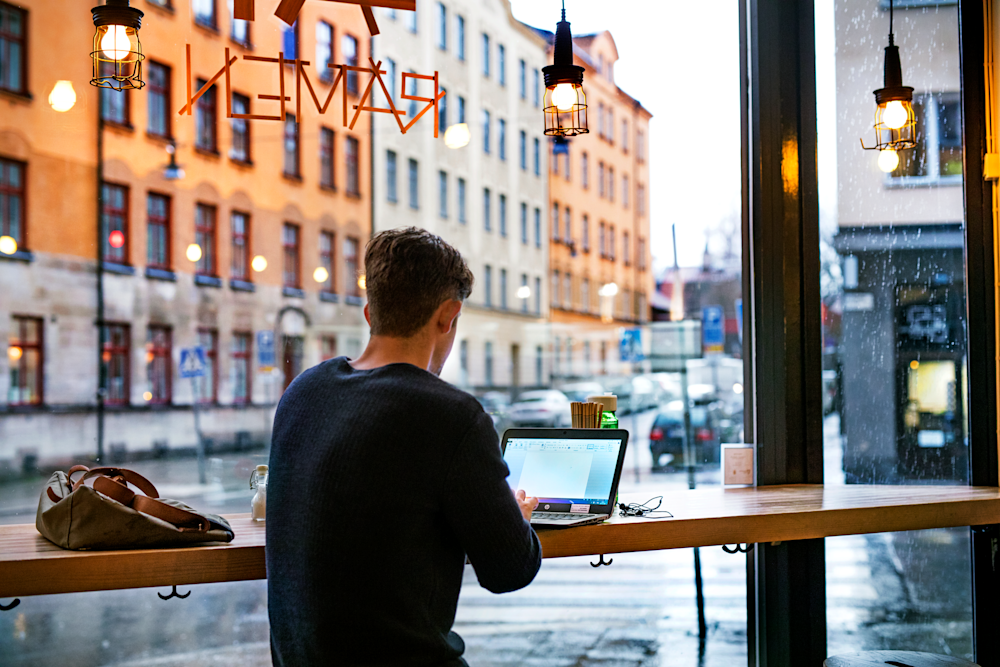 Man arbetar på laptop på restaurang.