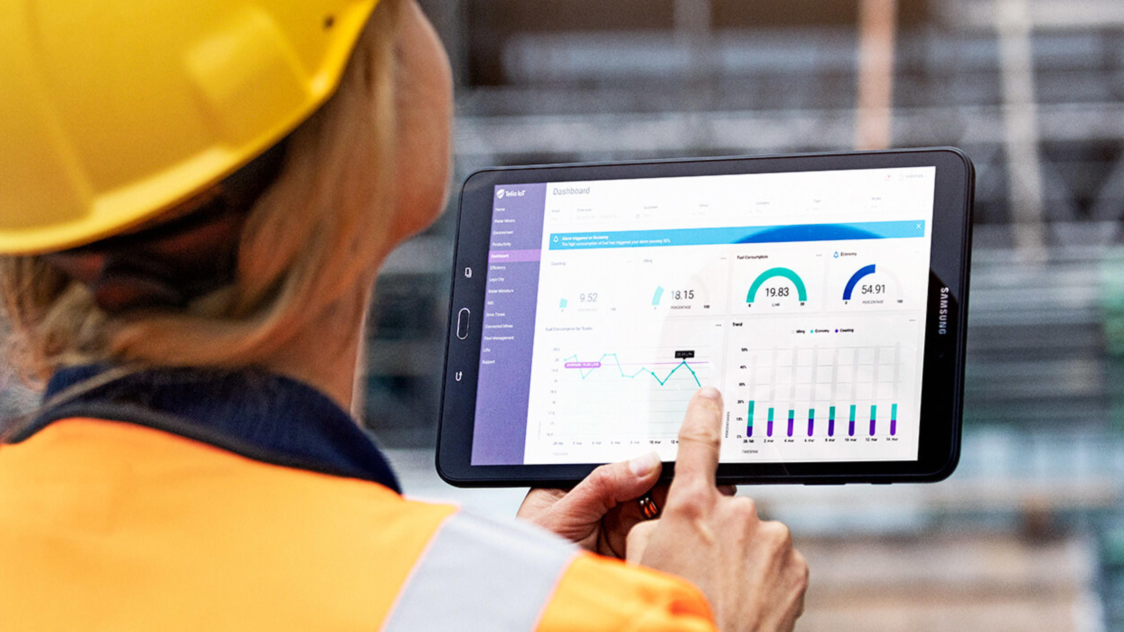 Kvinna med hjälm använder surfplatta på arbetsplats.