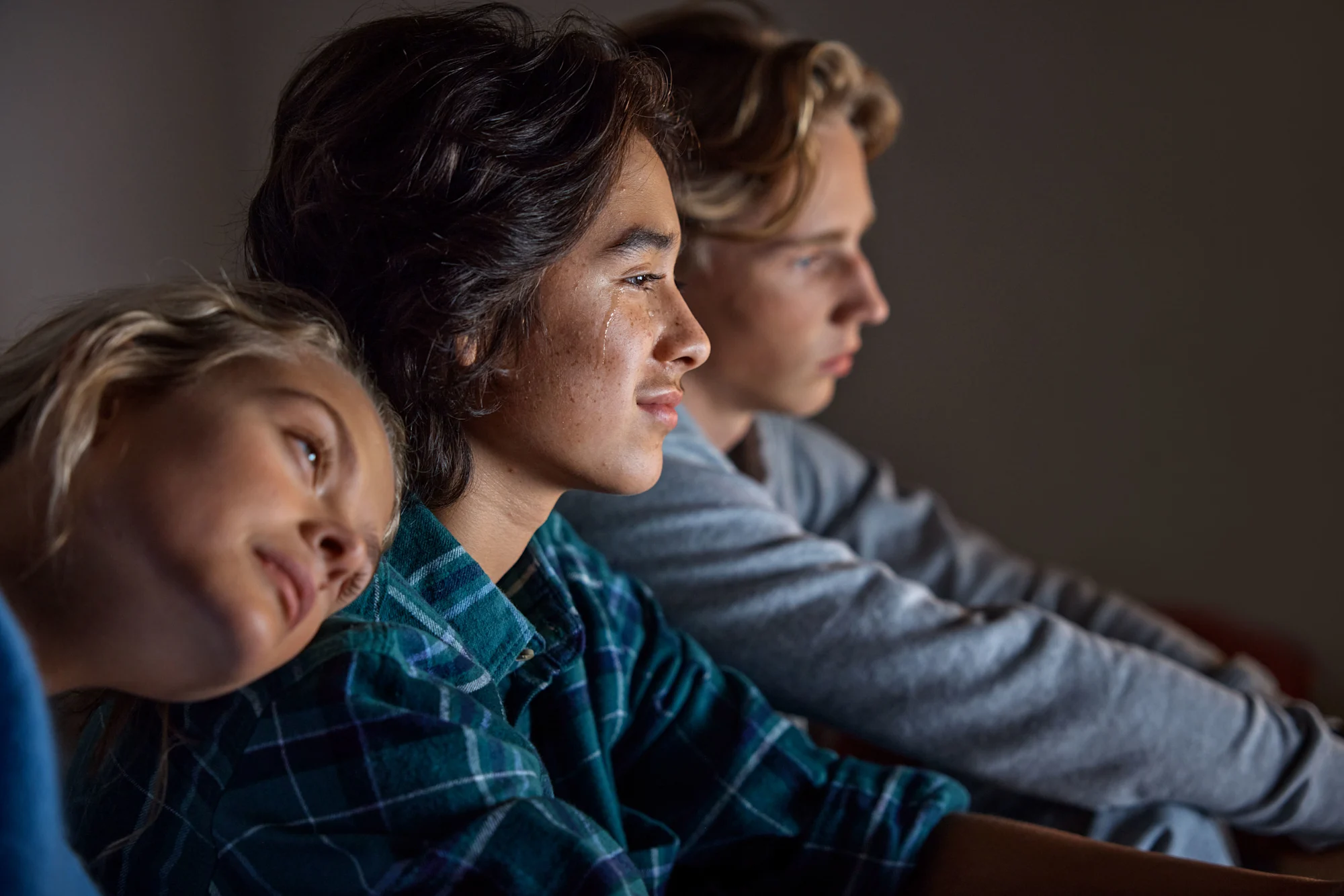 Ungdomar ser på tv tillsammans mysig stämning men något verkar sorgligt eller lyckligt