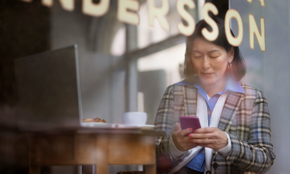Kvinna arbetar med sin jobbmobil i Telias nät på café