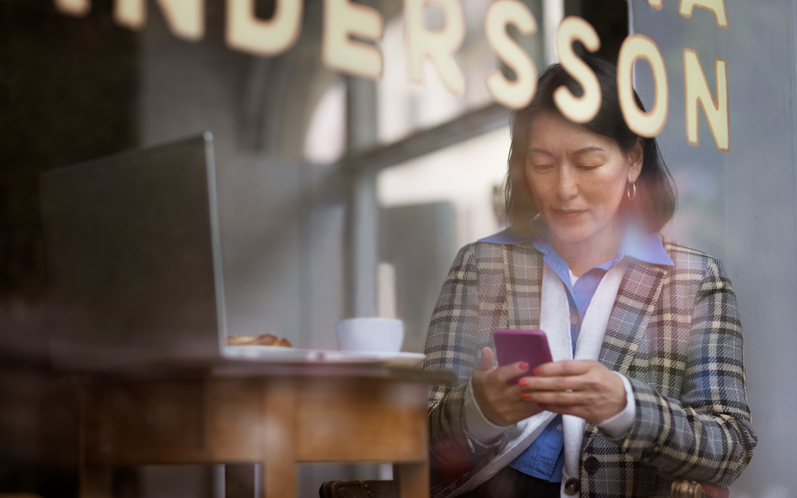 Kvinna arbetar med sin jobbmobil i Telias nät på café