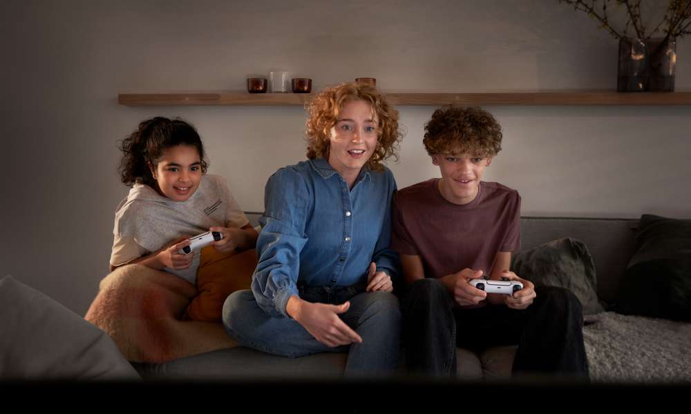 Kvinna och två barn spelar tv-spel tillsammans.