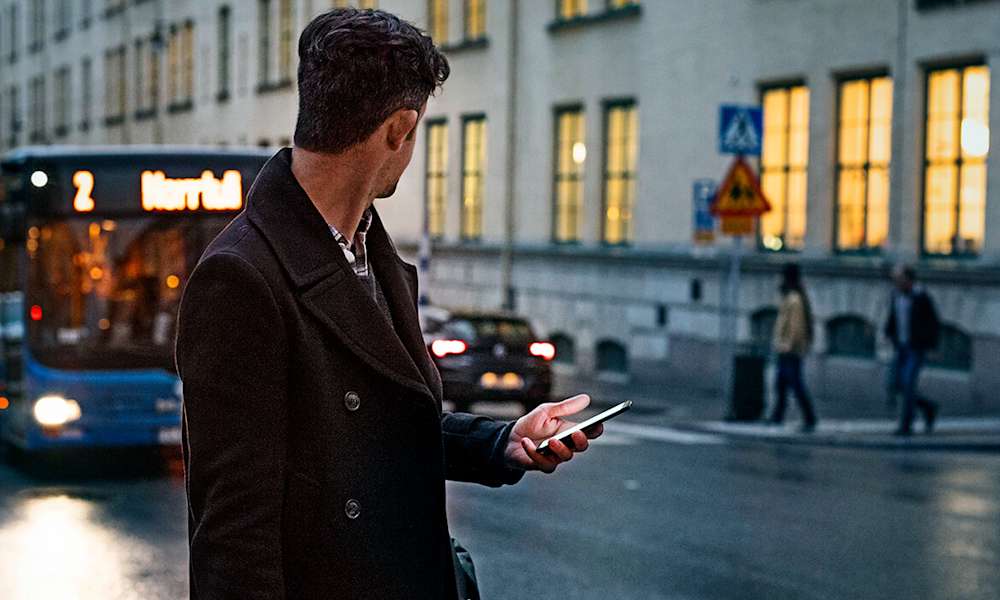 Man med mobil i en rulltrappa.