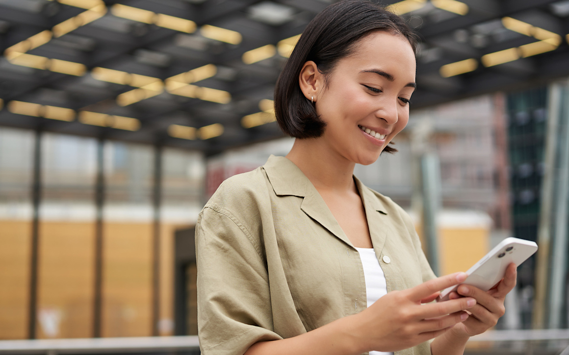 Kvinna kollar på mobil och ler