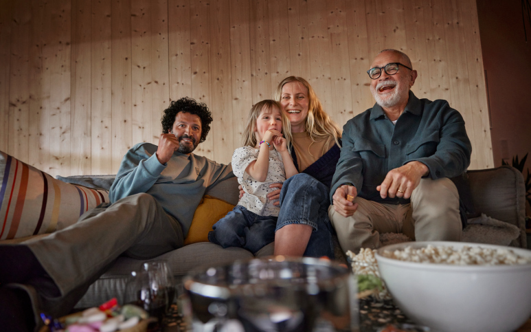 En glad familj tittar på tv och äter popcorn. 