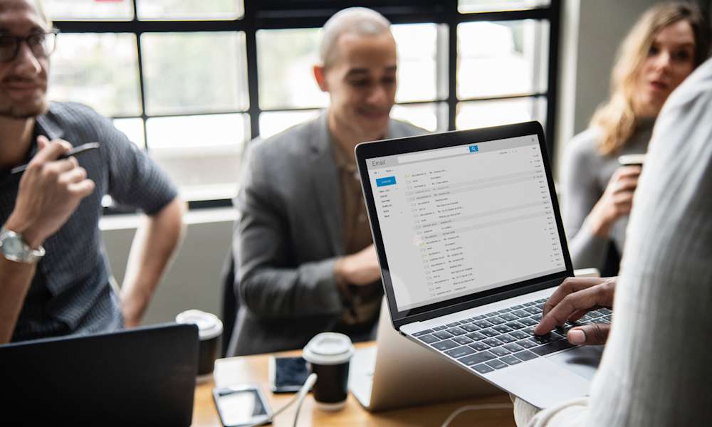 Folk sitter runt ett bord och arbetar på datorer