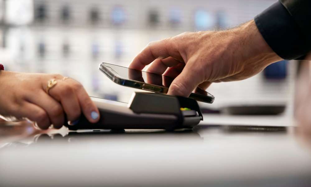 Person som betalar i kassaterminal med hjälp av mobiltelefon