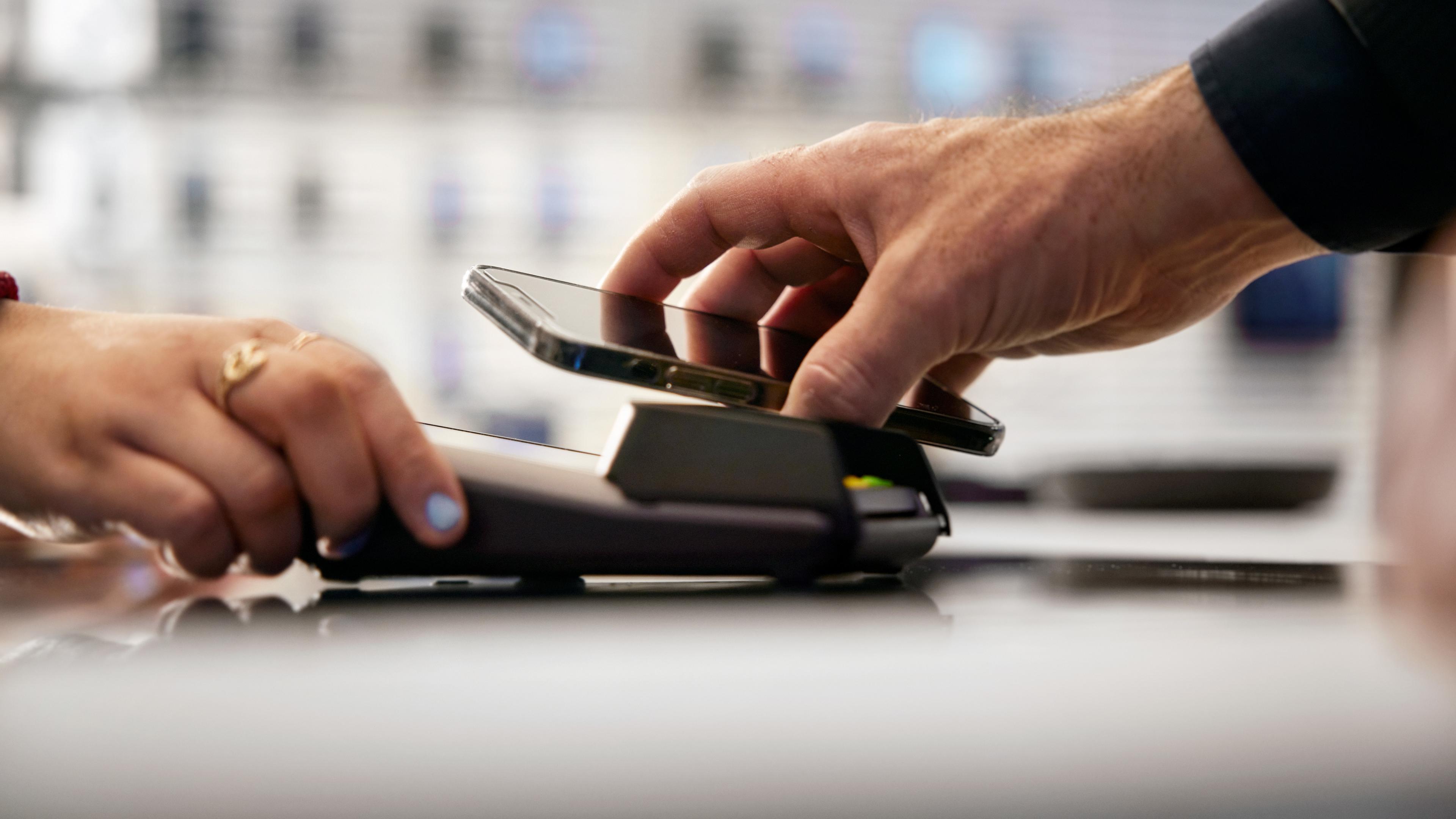 Person som betalar i kassaterminal med hjälp av mobiltelefon