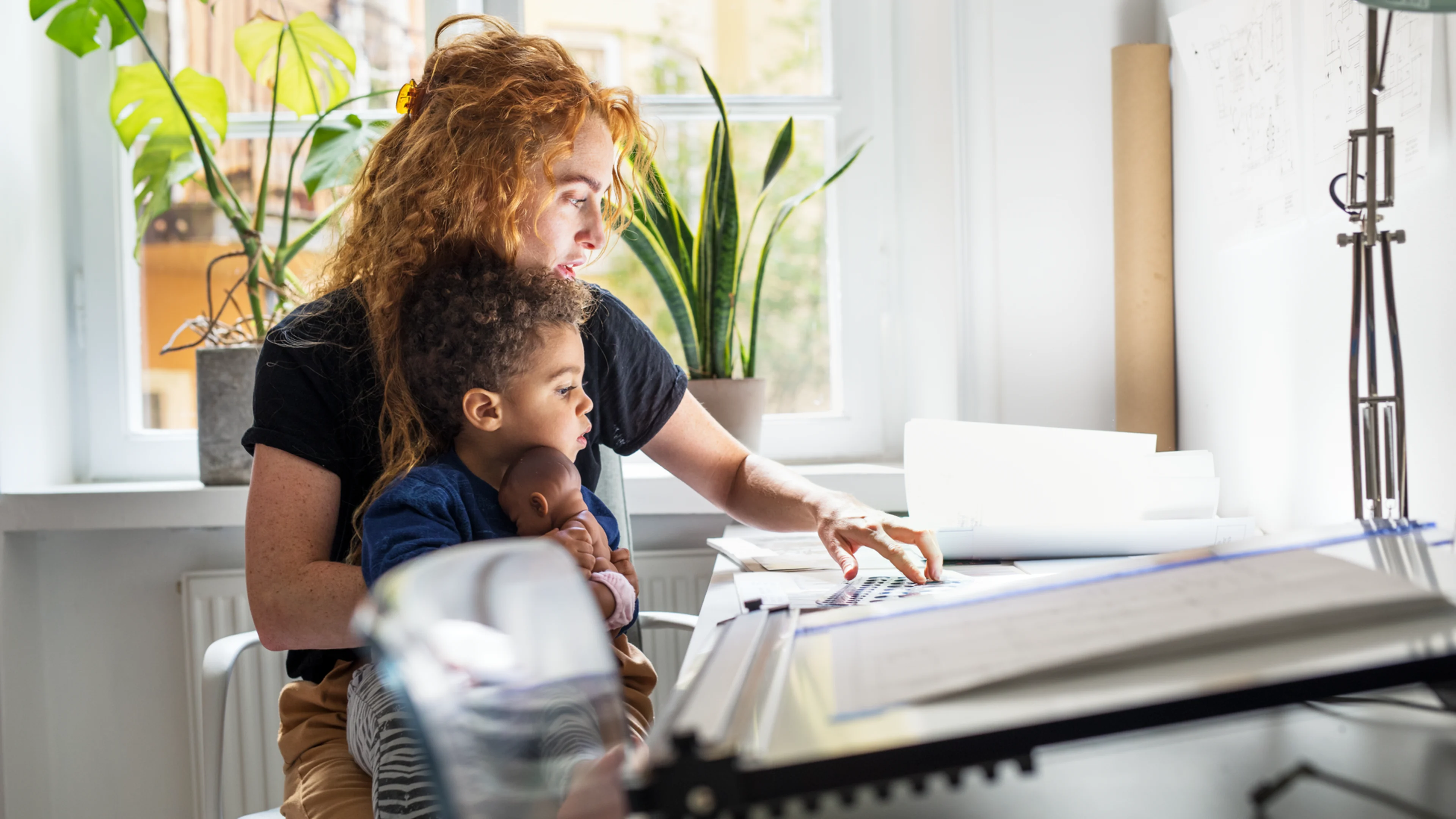 Kvinna på hemmakontor med barn i knät