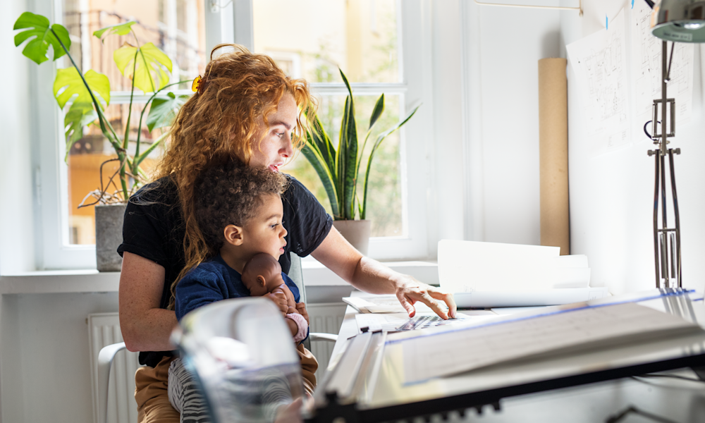 Kvinna på hemmakontor med barn i knät