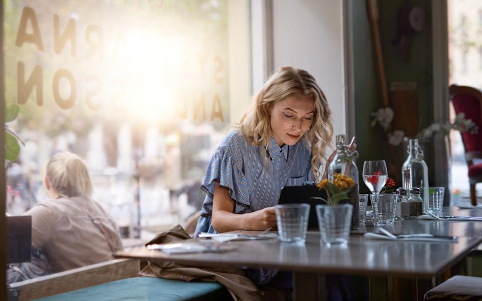 Kvinna arbetar på sin surfplatta vid ett restaurangbord.