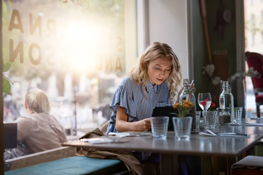 Kvinna arbetar på sin surfplatta vid ett restaurangbord.