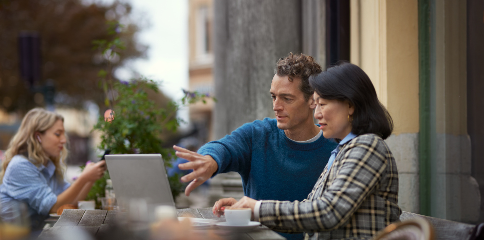 Man och kvinna arbetar på laptop med VPN på café utomhus.