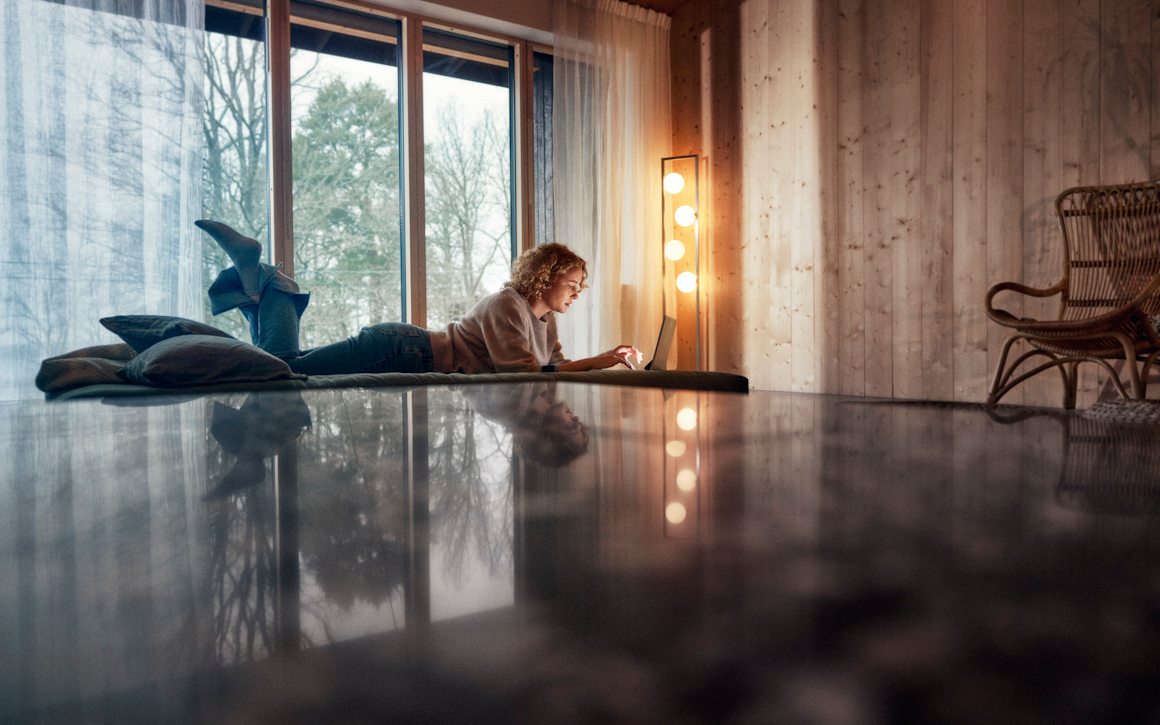 Kvinna ligger på golvet med en laptop-dator.