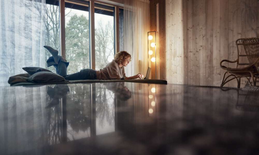 Kvinna igger på golvet med en laptop-dator.