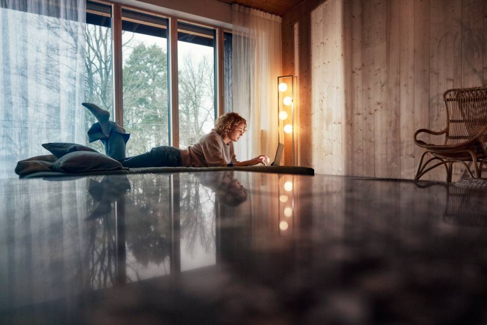 En tjej ligger på en säng och tittar på en dator.