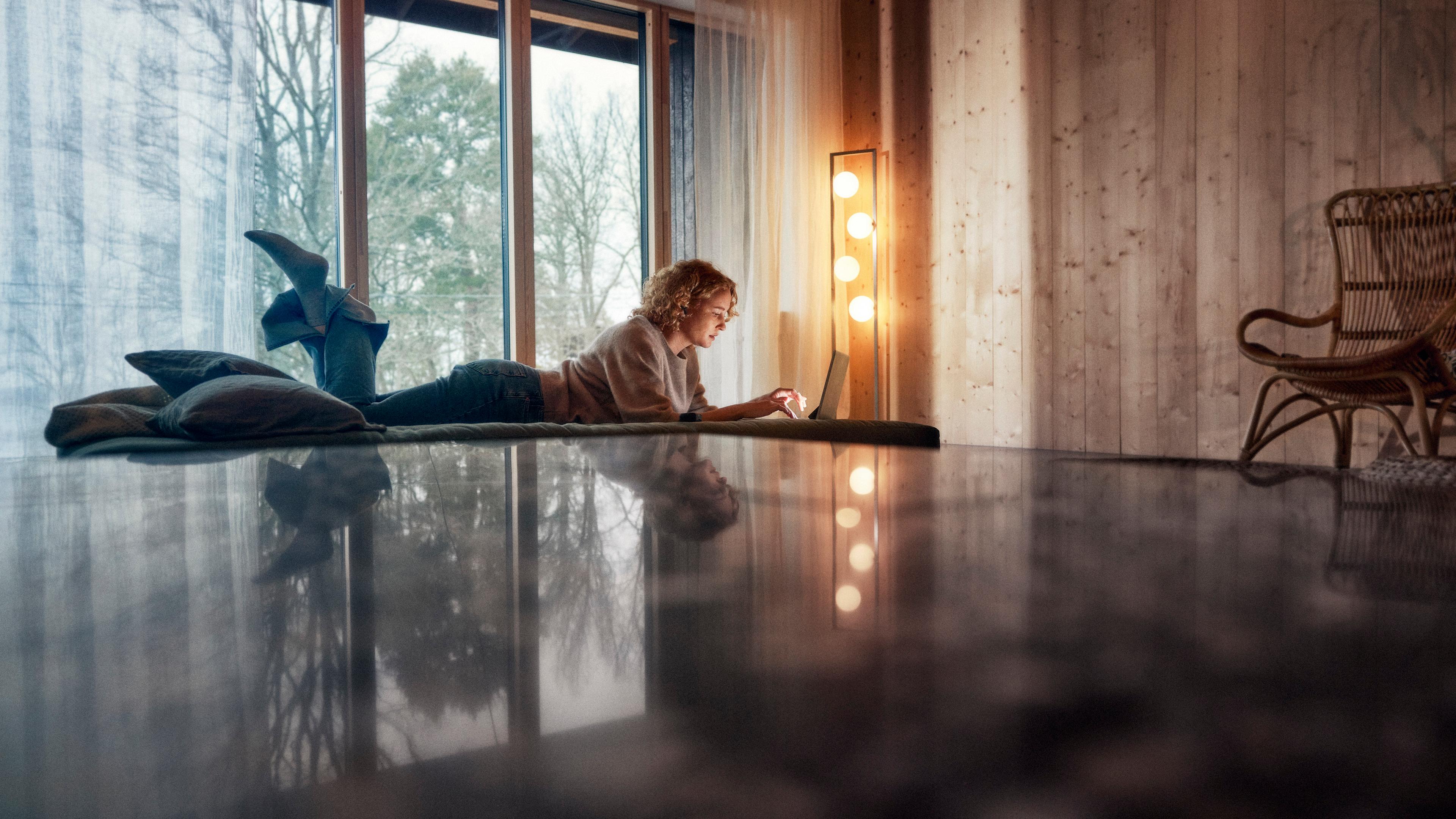 Kvinna ligger på golvet med en laptop-dator.