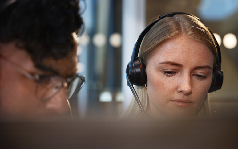 Kvinna med headset som tittar in i dator.