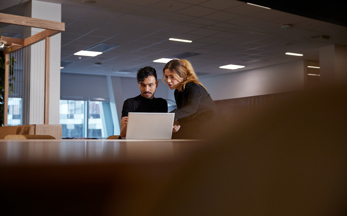 En kvinna står bredvid en man och visar honom något på en datorskärm