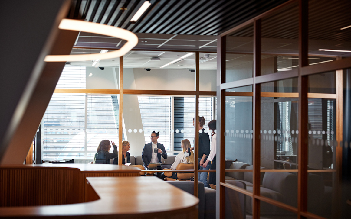 Personer som samtalar i ett konferensrum med väggar av glas.