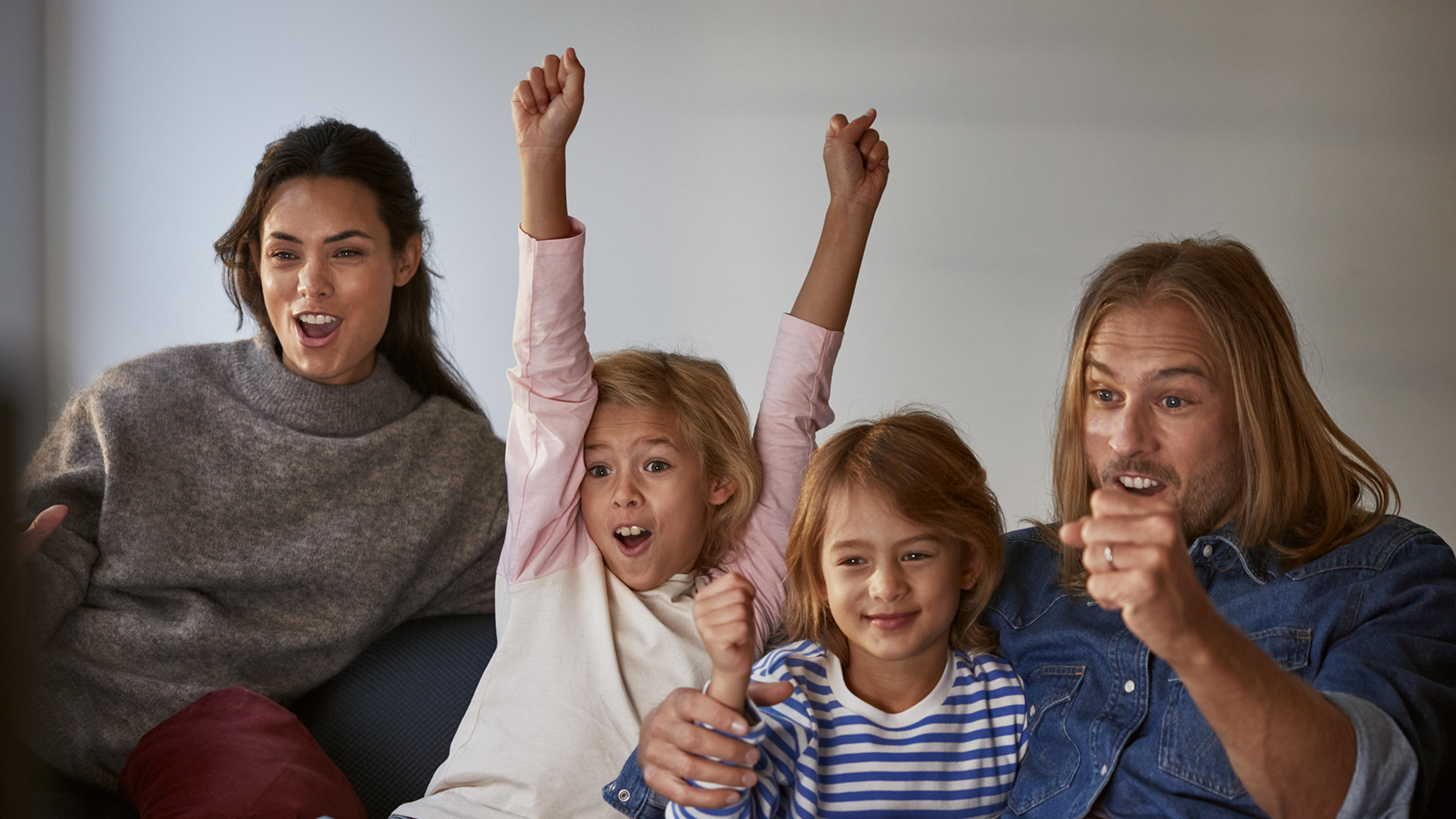 En glad familj tittar på tv och äter popcorn.