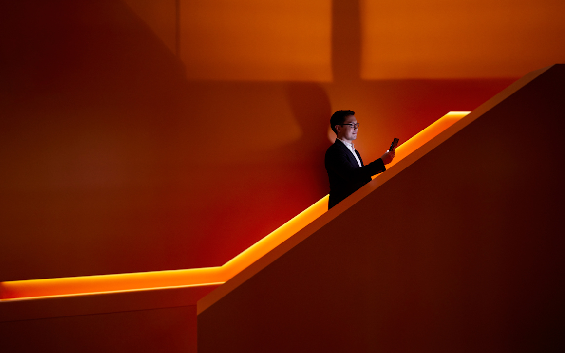 En man som åker rulltrappa uppåt och tittar på sin mobil