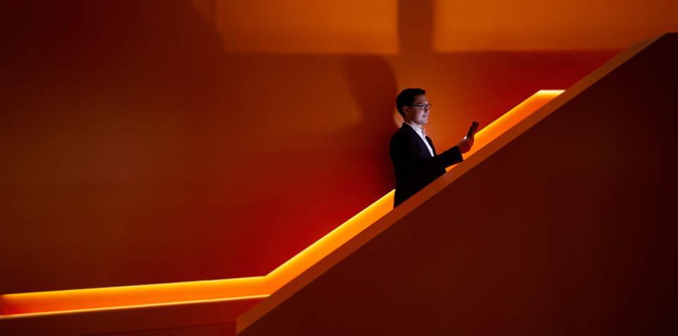 En man som åker rulltrappa uppåt och tittar på sin mobil
