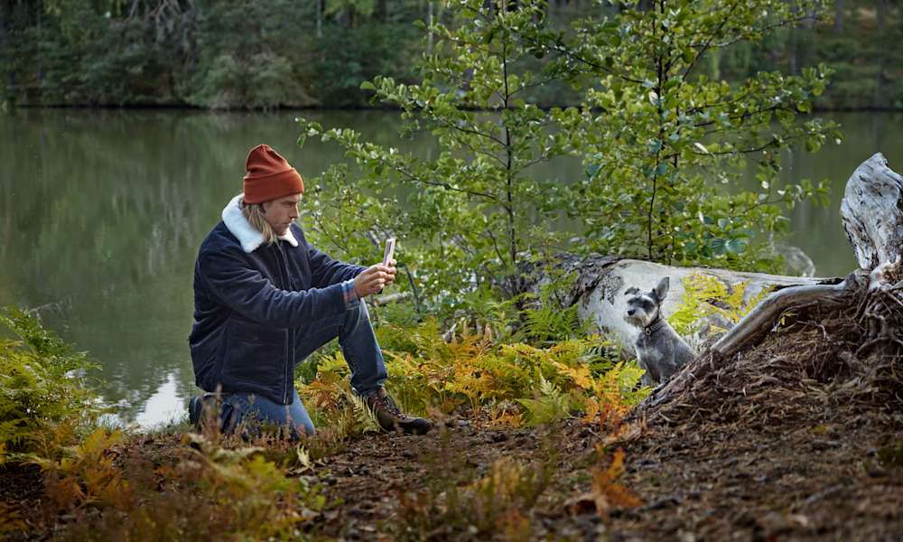 B2C - Man i naturen vid vatten fotar en hund