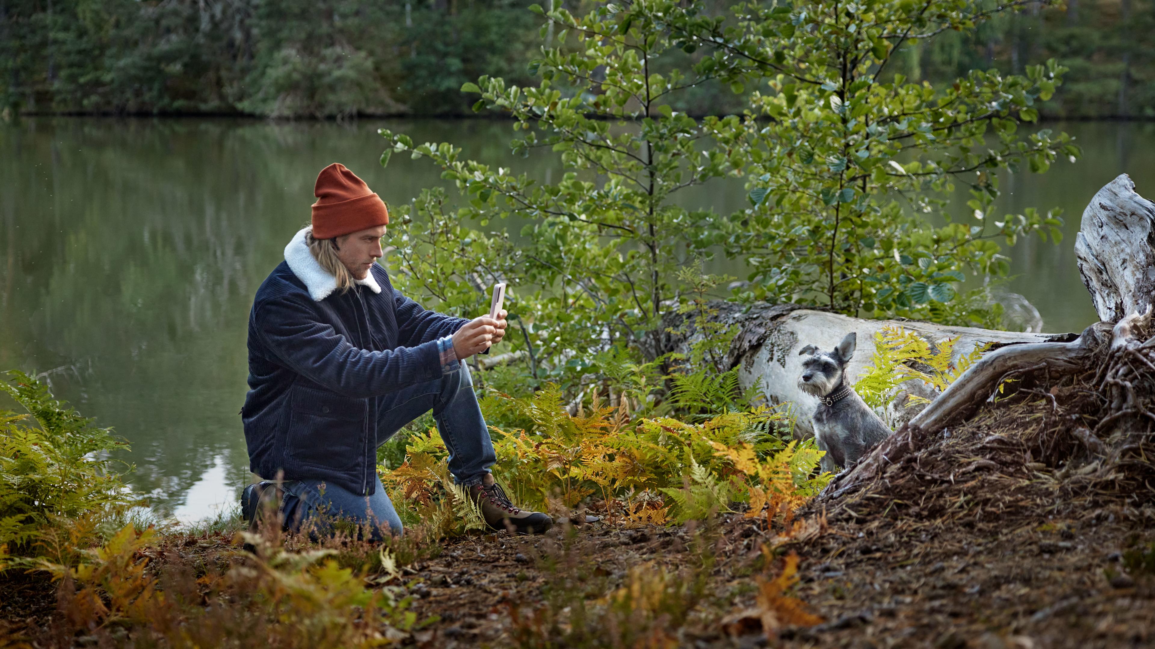 B2C - Man i naturen vid vatten fotar en hund