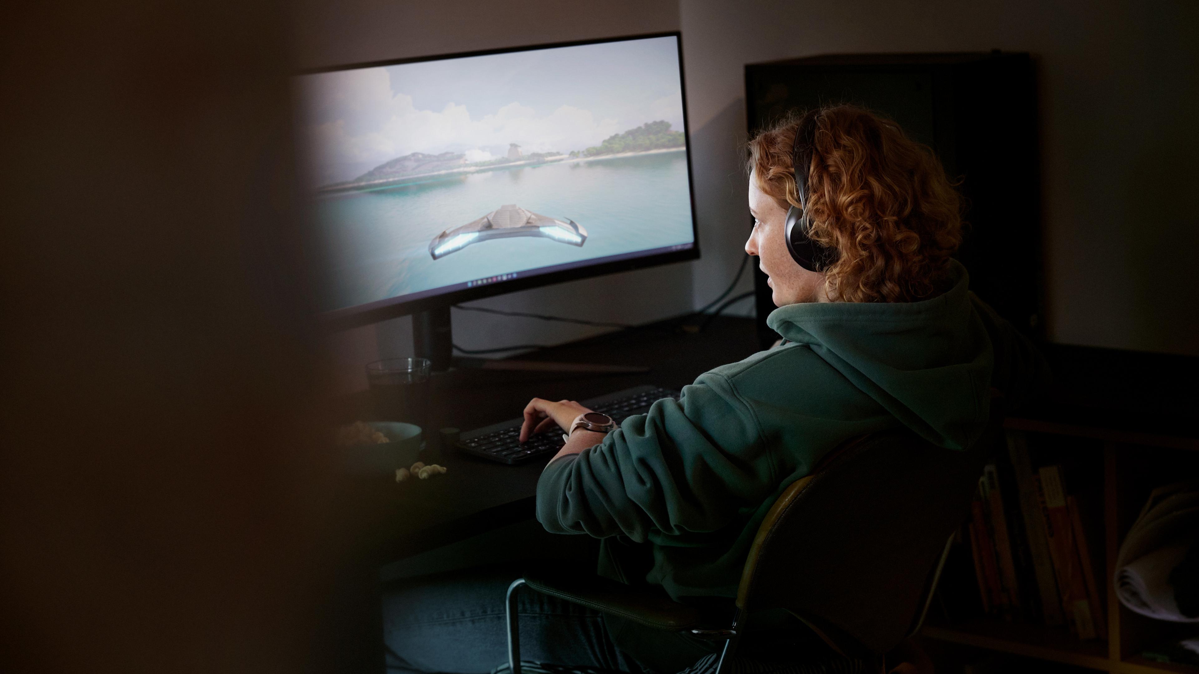 Kvinna spelar datorspel på en stor skärm.