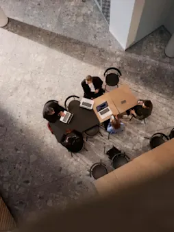 Konferensbord med arbetande människor och datorer sett ovanifrån.